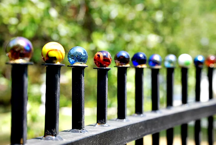 Металлический забор, украшенный цветными стеклянными шариками.