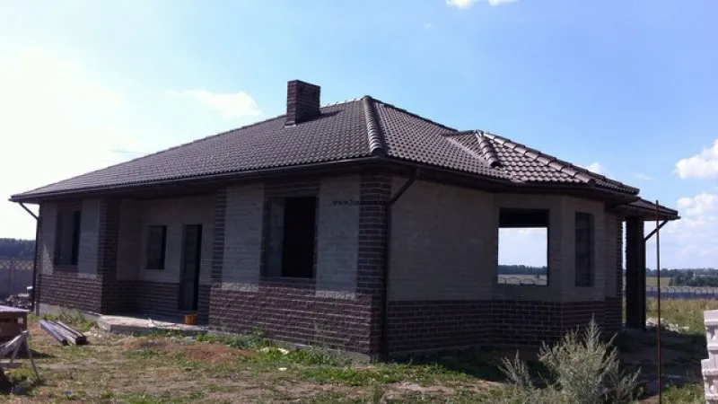 Экстерьер одноэтажного дома с вальмовой крышей облицован кирпичом