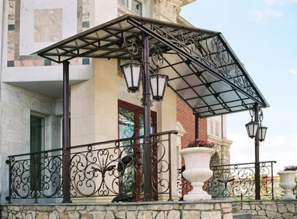 Двускатный козырек из поликарбоната украшает фасад достаточно дорогого дома